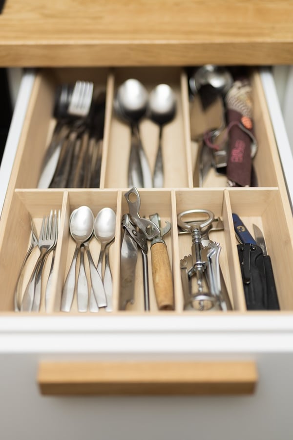 Close-up of neatly arranged cutlery in a drawer with compartments.