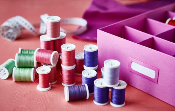 Close-up of reels of thread next to a purple box with interior compartments.