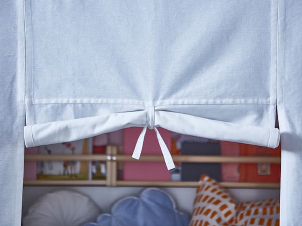 Close-up of the door of a kid’s bed privacy curtain rolled up and tied open.
