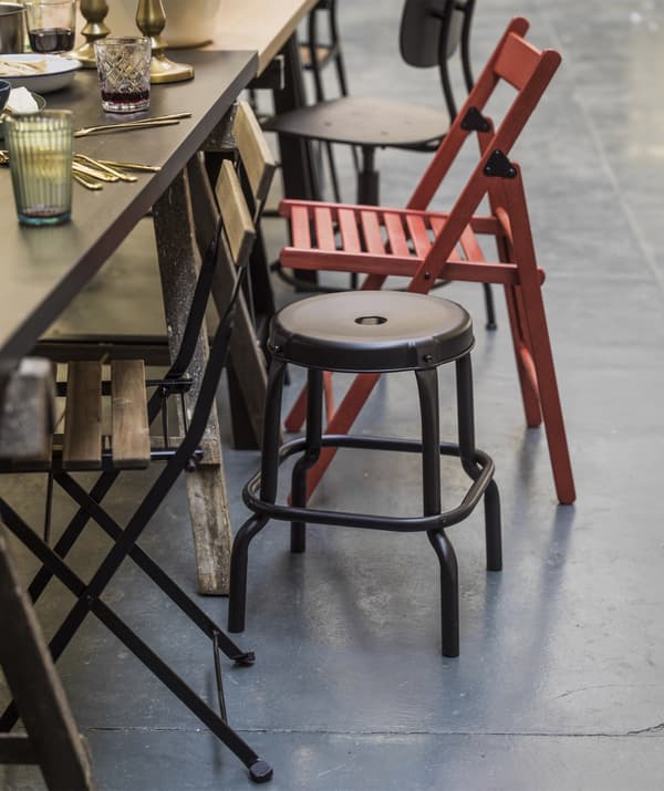 Close up of the edge of a dining table with mismatched chairs.