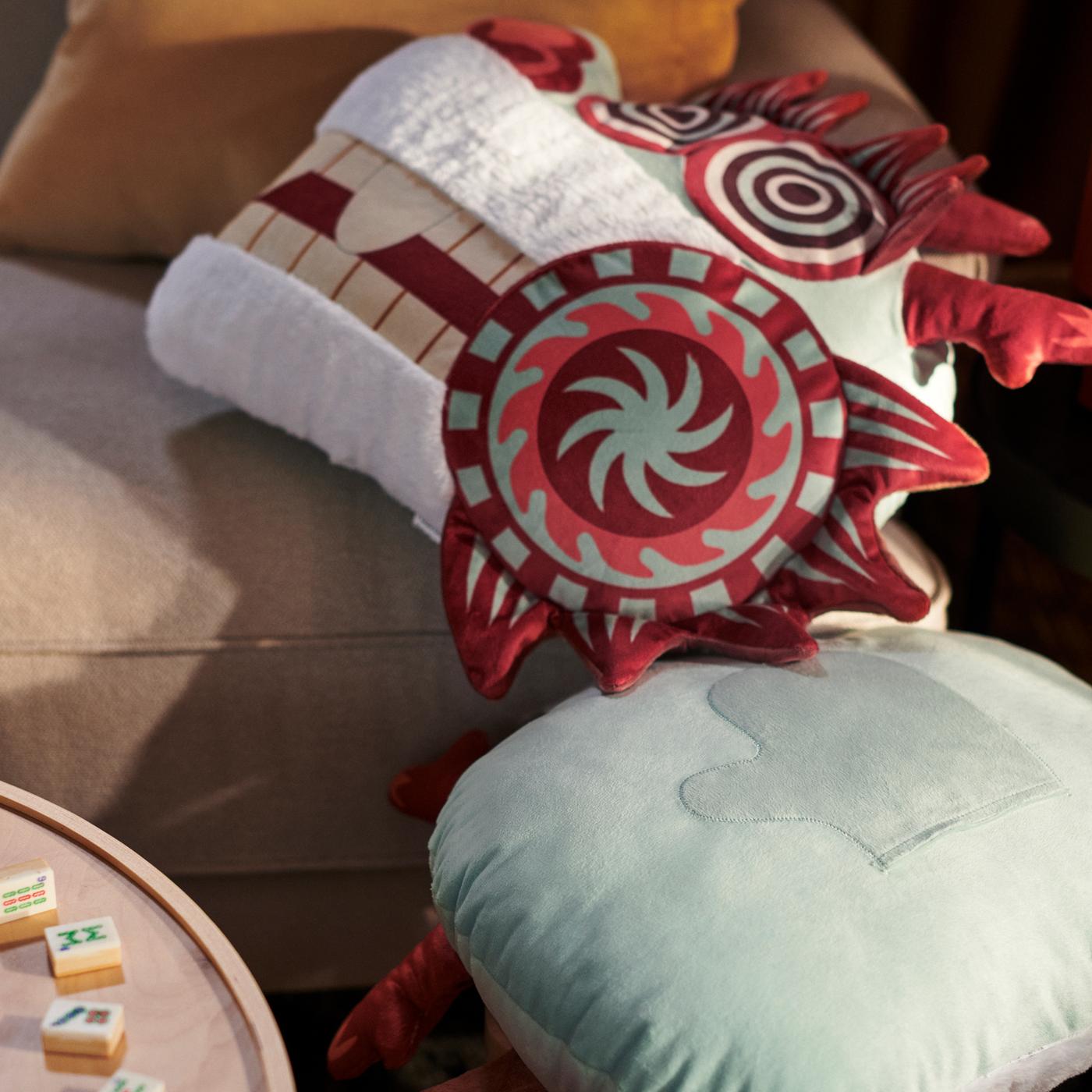 Close up of the FÖSSTA cushion cover that looks like a dragon’s head lying against the armrest of a sofa.