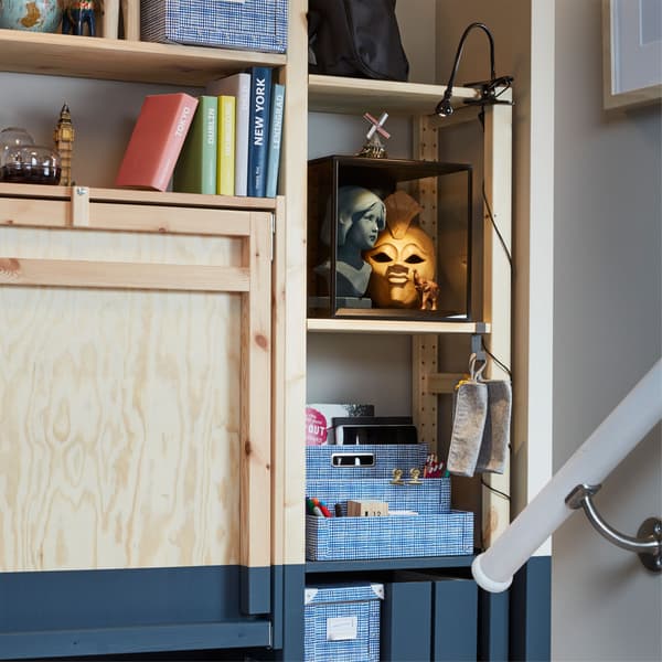 Close-up of the folded-up table of an IKEA IVAR storage unit, next to shelves containing hobby supplies and a display box.