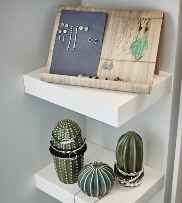 Close-up of the shelving unit inside the walk-in closet with RIMFORSA tablet stand in bamboo used as a jewelry display.