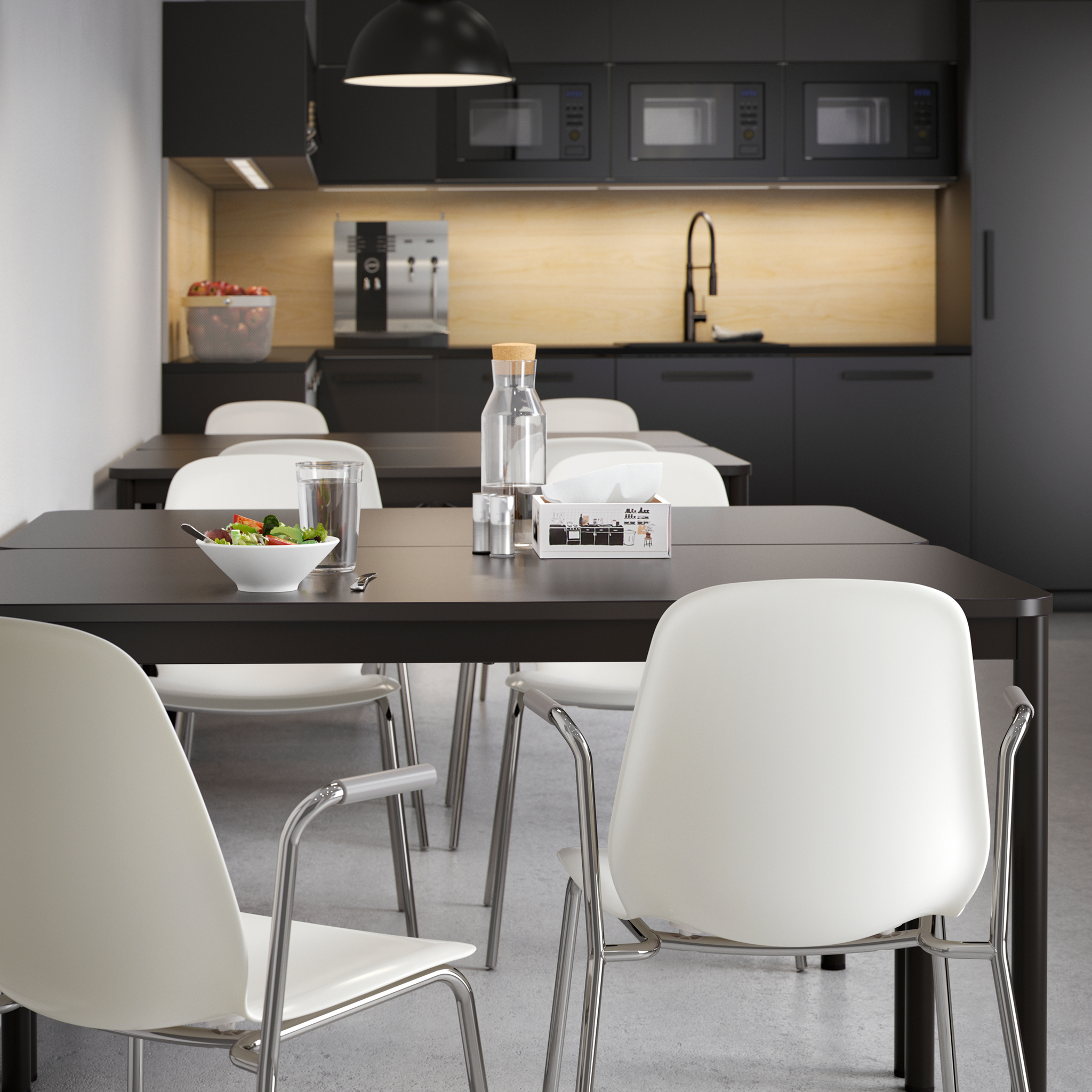 Close-up of two white chairs with armrests and the edge of an anthracite TOMMARYD table.
