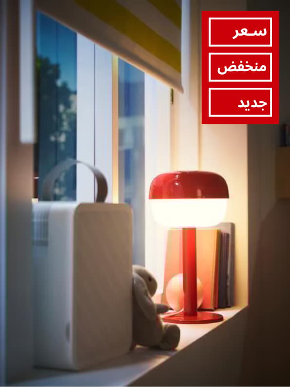 Close-up of window with a block-out roller blind, an UPPÅTVIND air-purifier and a table lamp standing on the window sill.