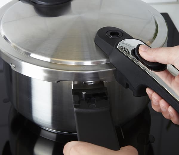 Close up photograph of a pressure cooker in stainless steel. 