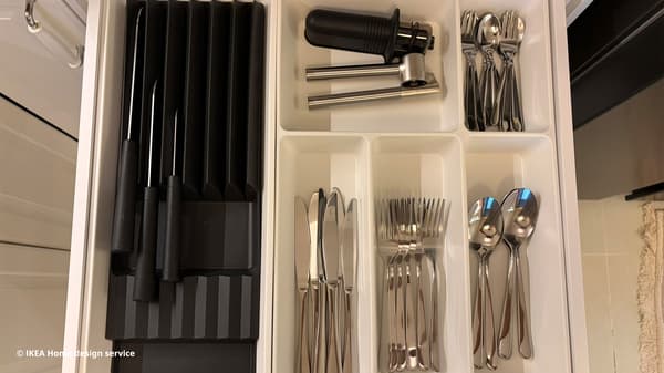 Close-up shot of knives and utensils in IKEA METOD kitchen drawer with white UPPDATERA drawer compartments.