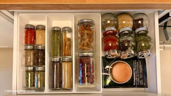 Close-up shot of spice jars in IKEA METOD kitchen drawer with white UPPDATERA drawer compartments.