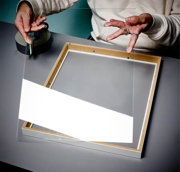 Close-up van handen die glas van een fotolijst verwijderen