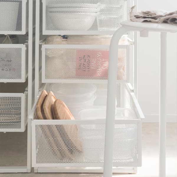 Close-up van twee IKEA LENNART ladeblokken achter een kruk, gevuld met tafelgerei en boodschappen.