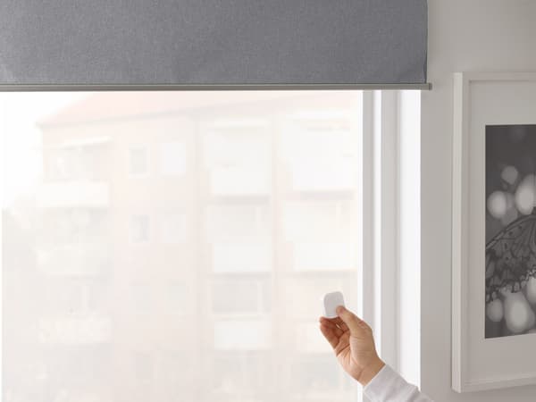 Close-up view of a hand holding a remote to control FYRTUR smart window blind.