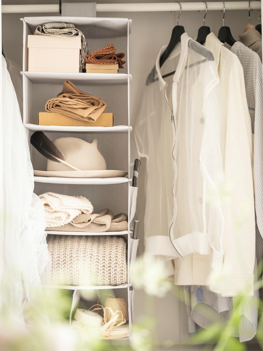 Closet con una barra de ropa con prendas colgando y cajas organizadoras