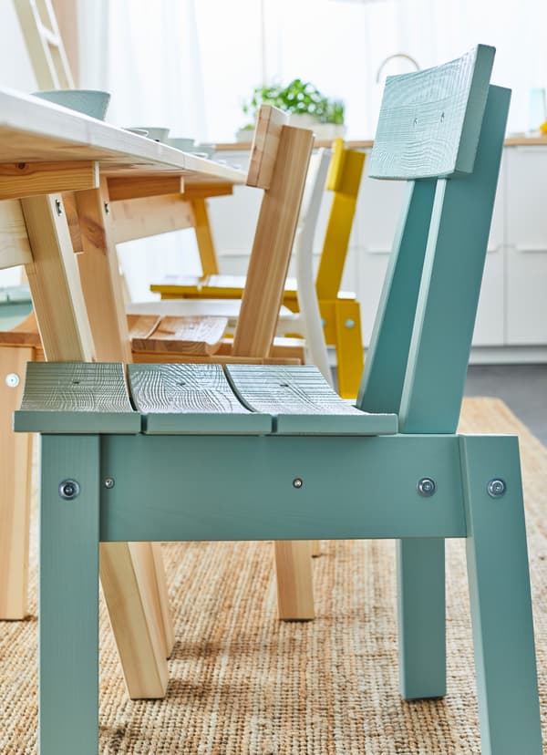 Closeup of an IKEA INDUSTRIELL blue seat by a dining table.
