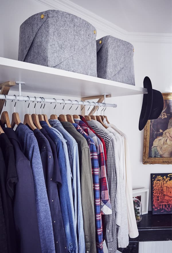 Clothes hang in an open-storage wardrobe.