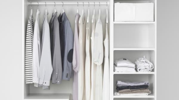 Clothes hanging in a closet with shelves holding folded clothes