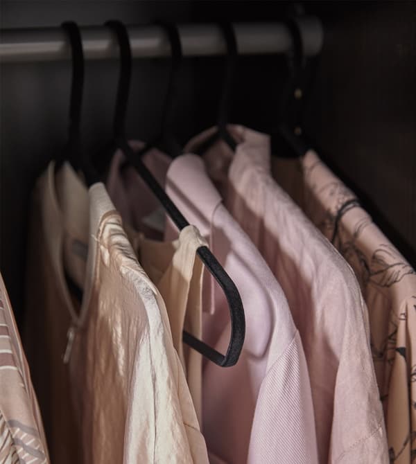 Clothes hanging on STRYKIS clothes hangers that are made of sturdy steel covered in velvety, black nylon.
