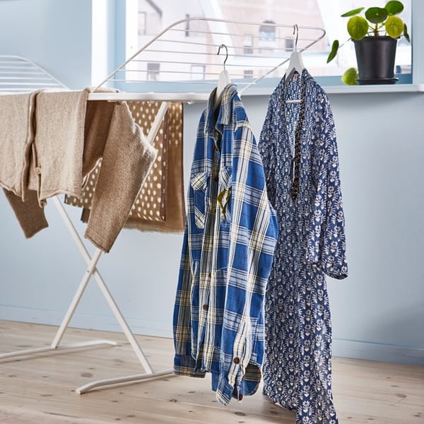 Clothes hanging to dry on an indoor drying rack beside a window.