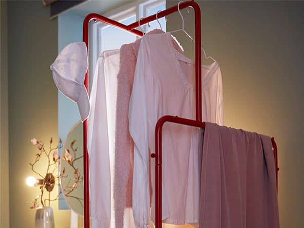 Clothes rack with garments and shoes placed perpendicular to the wall, as a room divider between recliner and make-up spot.