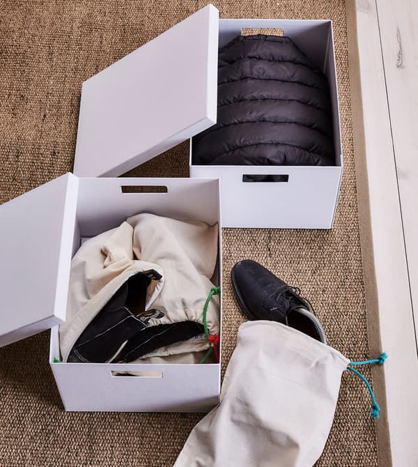 Clothing and shoes are placed in paper boxes to be stored.