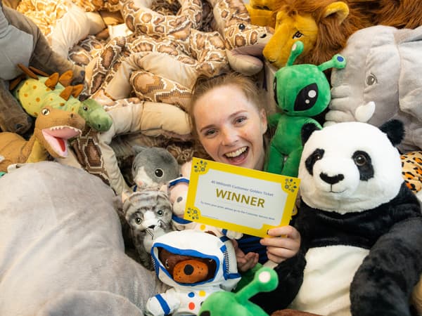 Co-worker together with lots of animal soft toys holding a golden ticket