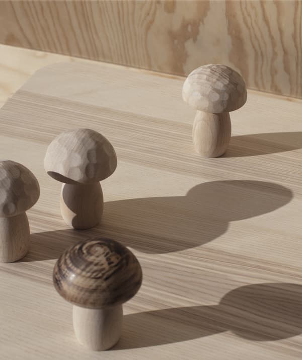 Cogomelos tallados en madeira da colección IKEA ANNANSTANS sobre unha superficie de madeira.