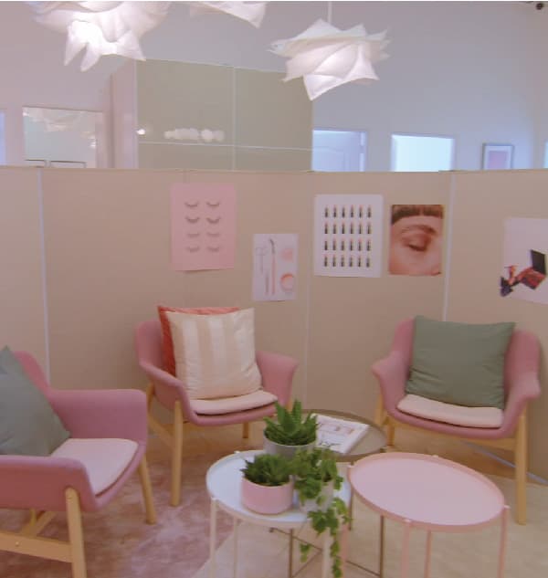 Coin attente avec trois fauteuils roses et 3 petites tables basses décorées de plantes vertes.