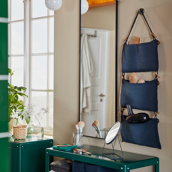 Coin beauté comprenant rangement suspendu NORDRANA, miroir fixé au mur et étagère verte.