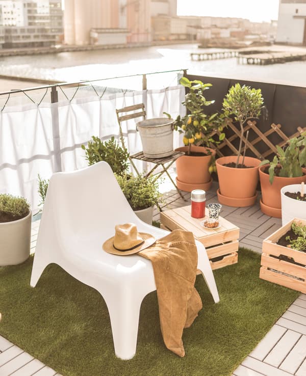 Coin détente sur le toit aménagé avec un fauteuil et un cageot en bois en guise de petite table.