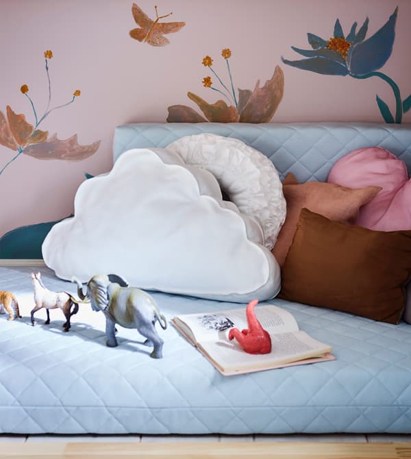 Coin jeu cosy pour enfant réalisé avec des coussins et un matelas pour lit extensible.