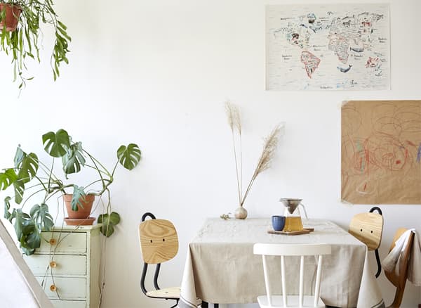 Coin repas blanc avec chaises en bois et faux philodendron.