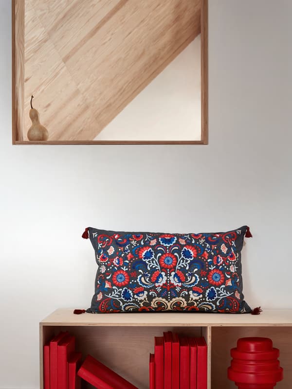 Cojín SKOGSKORN con bordado floral de estilo tradicional y borlas en las esquinas.