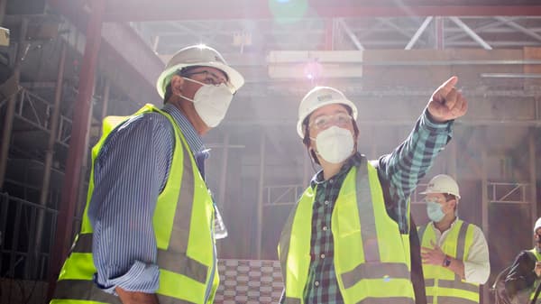 Colaboradores de IKEA en visita a terreno de la zona de construcción y levantamiento de la primera tienda IKEA en Chile. Usan chalecos amarillos para verse y por seguridad, junto con cascos blancos. El jefe de obra da indicaciones e instrucciones con el dedo a los visitantes.