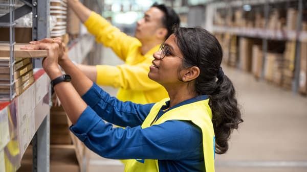 Colaboradores IKEA com fardas em azul escuro a inspecionar os tabuleiros de alfaces.