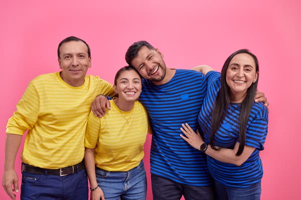 Colaboradores IKEA vestidos con su uniforme amarillo y azul saludando con un fondo fucsia.