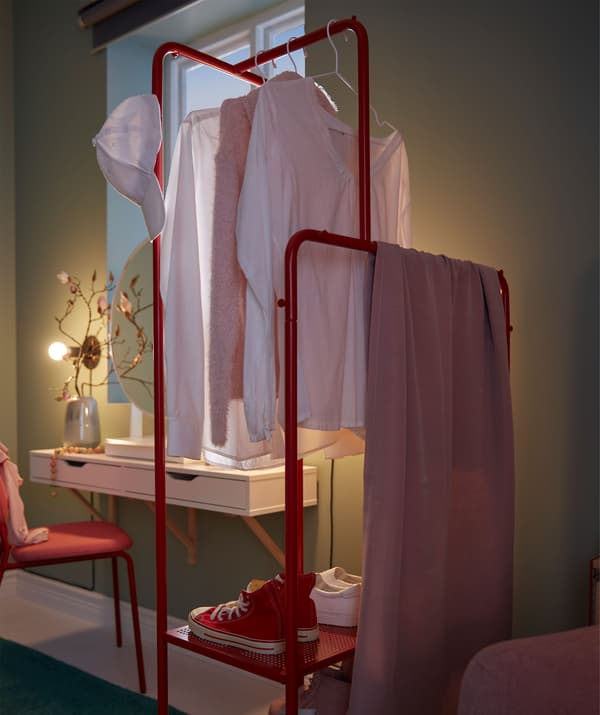 Colgadoiro con roupa e zapatos colocados de forma perpendicular á parede, como separador de ambientes entre a cadeira de brazos e o toucador.