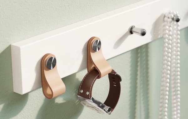 Colgadoiro IKEA LURT branco con seis ganchos cun reloxo e bixutería.