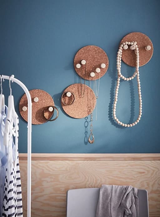 Colgadores de joyas hechos con corchos sobre una pared azul.