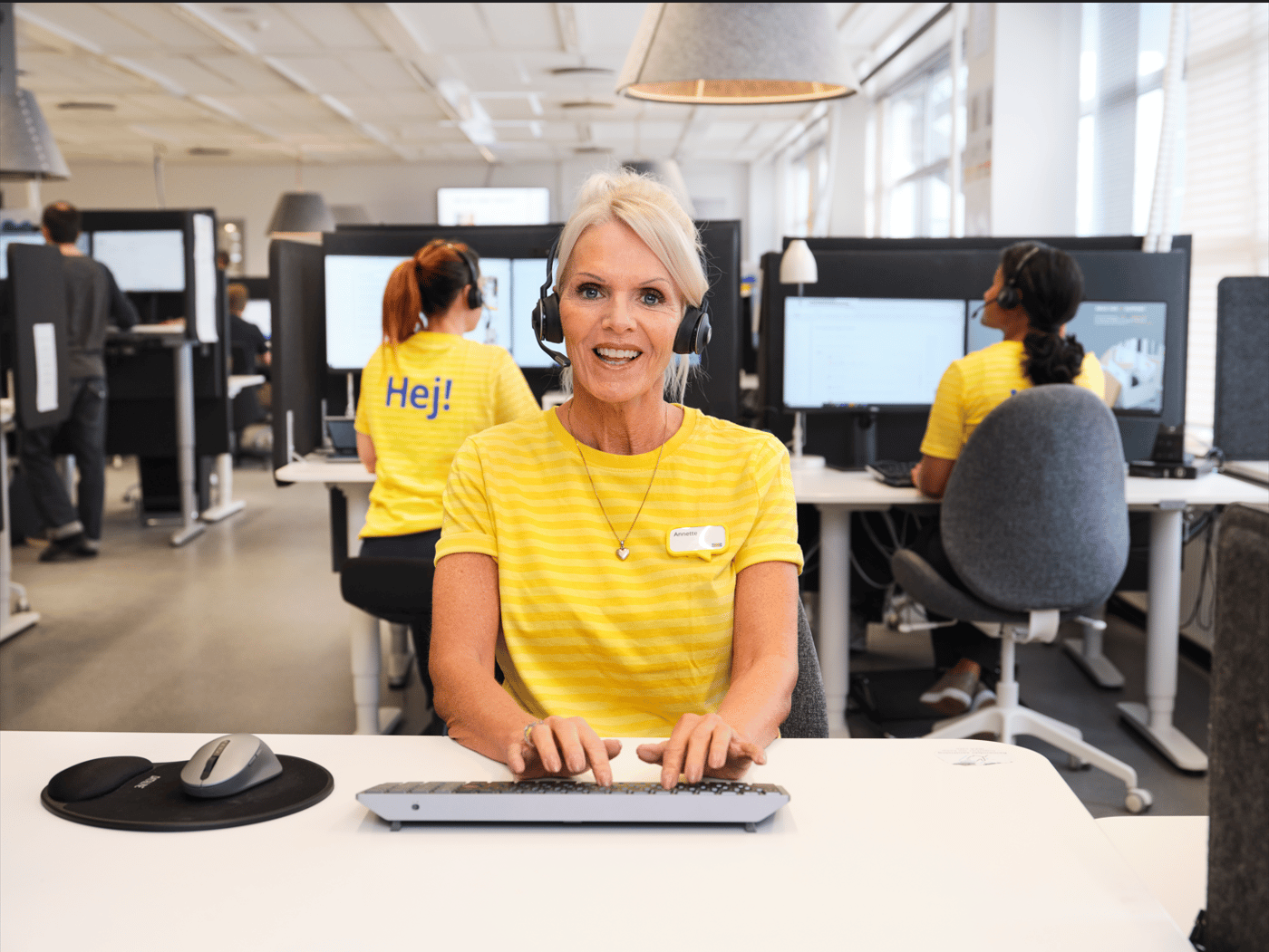 Collaboratrice IKEA avec un casque en train de taper sur son clavier.