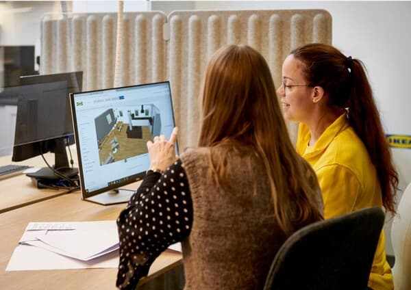 Collaboratrice IKEA travaillant le projet d'une cliente avec elle sur un pc