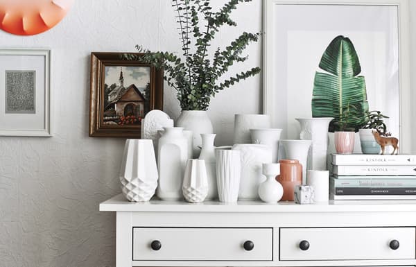 Collection de vases blancs sur une commode.