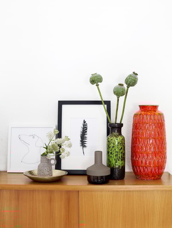 Collection de vases et de reproductions sur le dessus d’une armoire.