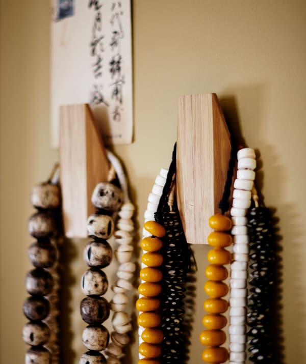 Colliers de perles accrochés à deux crochets en bois.