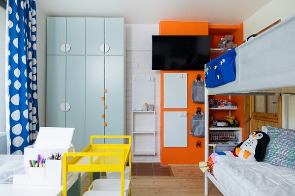 Colorful children’s bedroom with bunk bed, wardrobe, TV, and toy storage