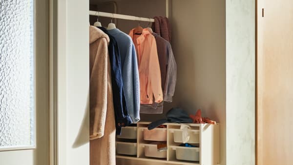 Colourful clothes on clothing rack in well-lit hallway with small organisers on wall