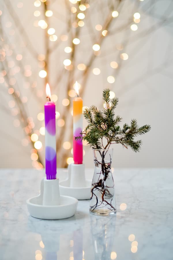 Colourful, decorative candles in a white candle holder on a table