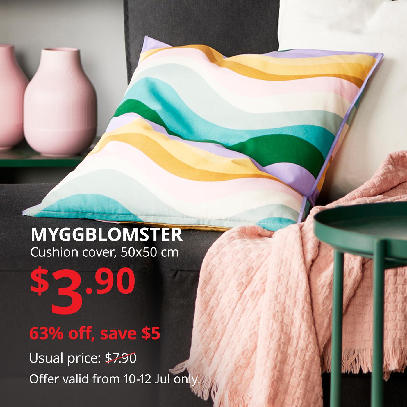 Colourful striped MYGGBLOMSTER cushion on a sofa with a patterned throw blanket.