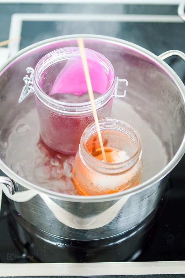 Colourful wax in glass containers heated in hot water