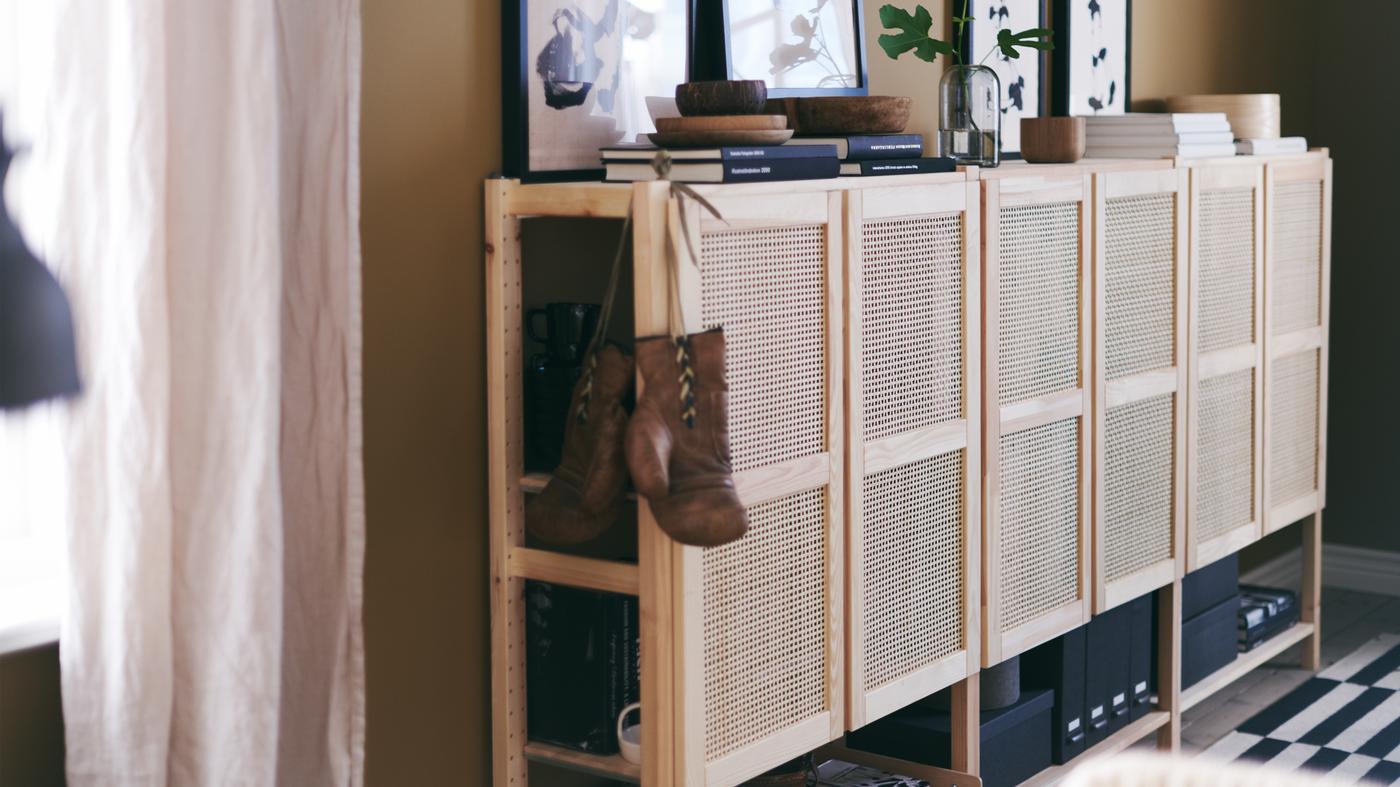 Combinação ampla de armários IVAR com portas de bambu entrançado decorada com livros, peças de arte e outros objetos pessoais.