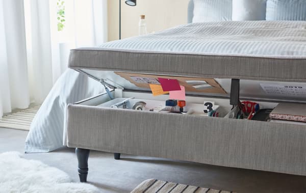 Combinaison banquette/rangement recouverte de textile. Installée au pied du lit, elle dévoile différents objets destinés à un travail de bureau à domicile.