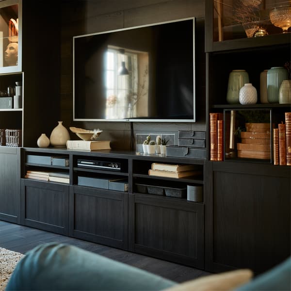 Combinaison rangement TV BESTÅ en noir-brun sur laquelle sont placés un téléviseur, des livres, des vases et de petites plantes.
